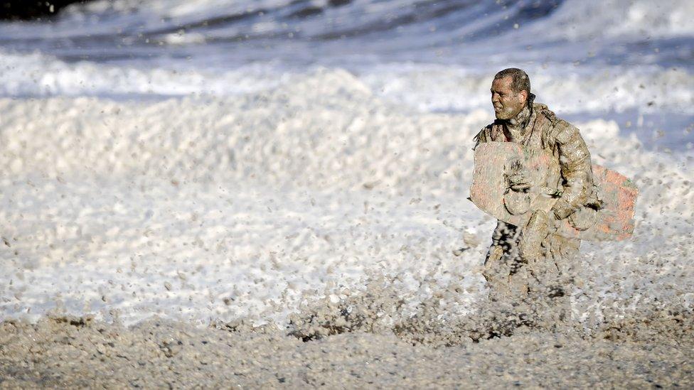 A rescue worker stands in rough waters during the resumed search for missing water sports participants in The North Sea at Scheveningen