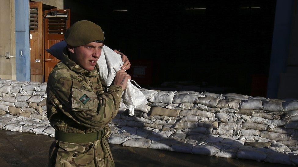 A soldier carrying a sandbag