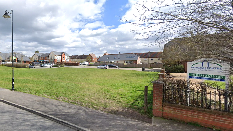 A street view showing a green space bordered with new build houses