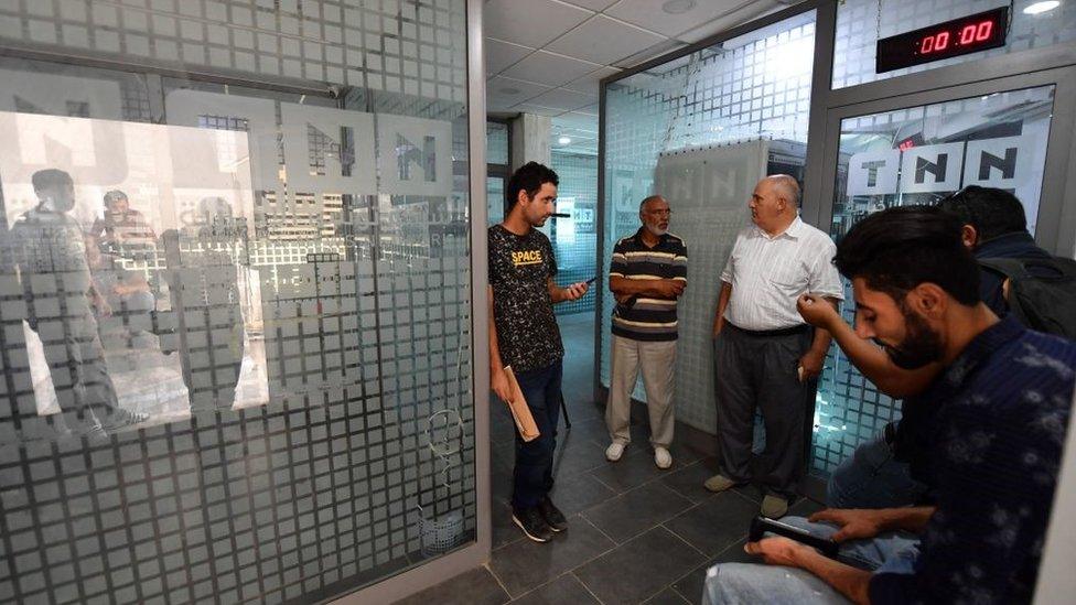 Employees gather inside the building housing the Zitouna TV channel gather on October 6, 2021, after Tunisian authorities seized broadcasting equipment