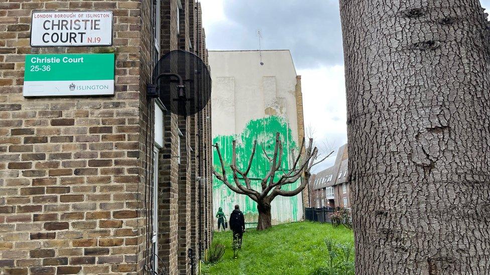 The signs for Christie Court with the mural of a tree in the background