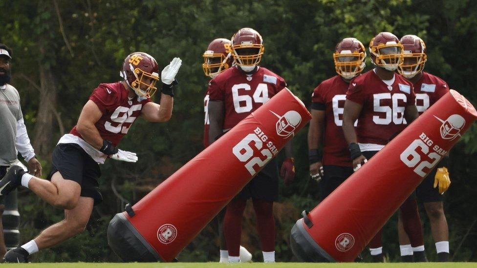 Washington Football Team defensive end Casey Toohill (L) runs around blocking dummies during drills