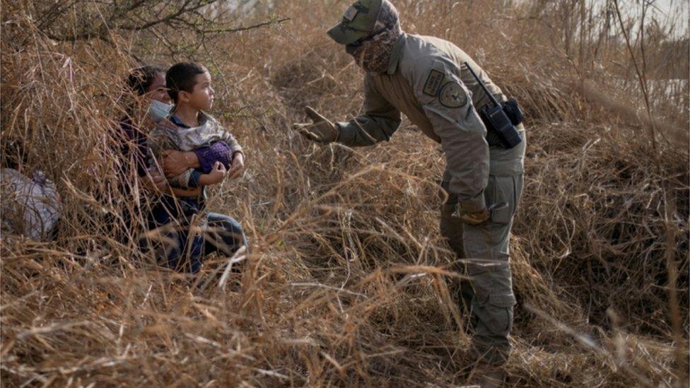 Migrants crossing into the US are stopped by an official in Texas