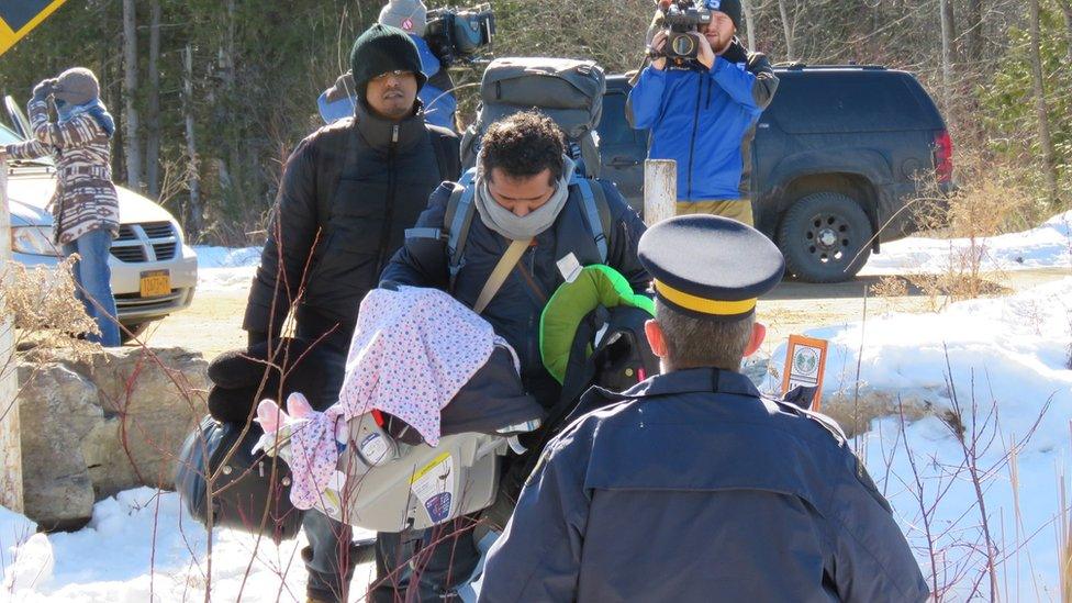 A group of asylum seekers cross the border illegally from the United States into Canada