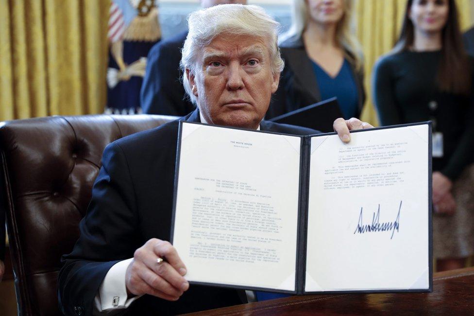 US President Donald Trump displays one of five executive orders he signed related to the oil pipeline industry in the oval office of the White House in Washington, DC, USA, 24 January 2017