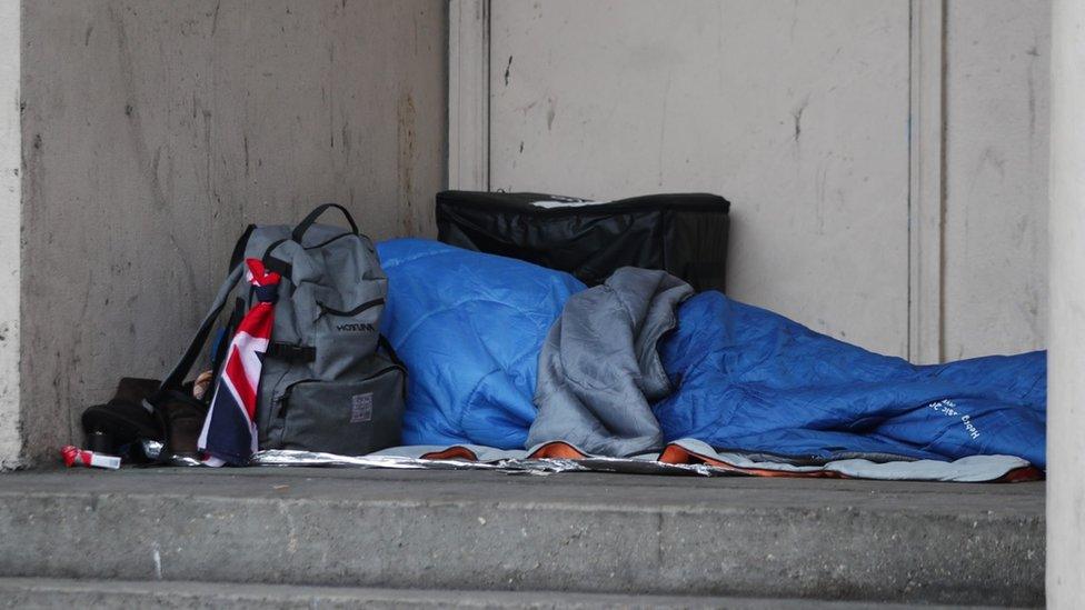 A homeless person sleeping rough in a doorway