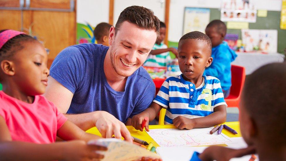 A volunteer teacher sitting with young children in a classroom