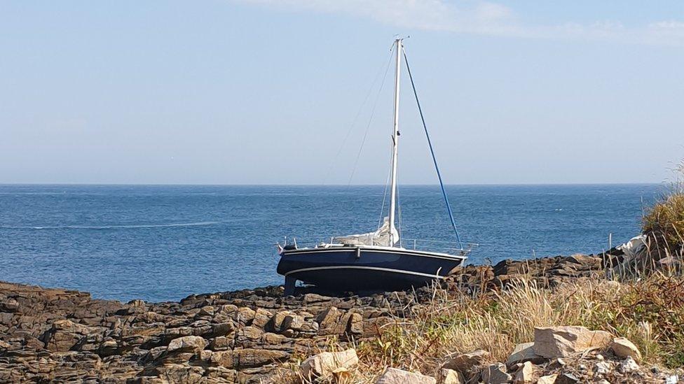 Yacht on a rocky gully off Raz at Longis Bay, Alderney