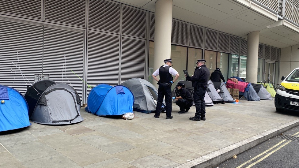 Image showing a female officer bent down talking to someone inside a tent on the street