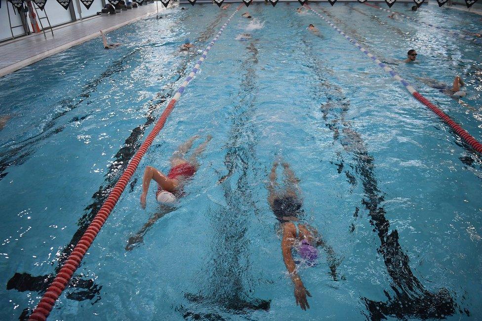 People swim in lanes at an indoor swimming pool