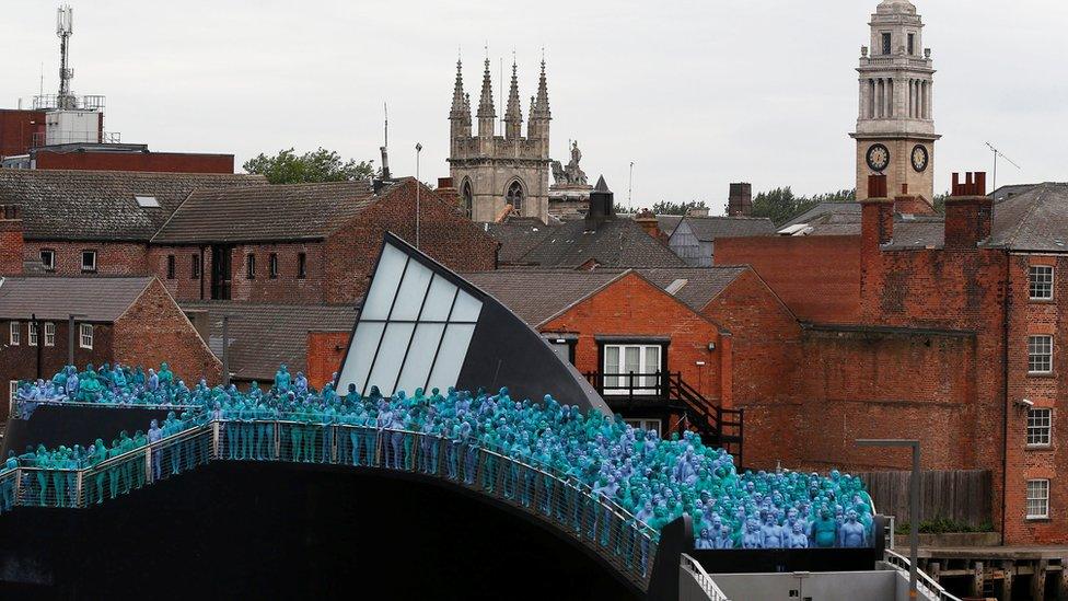 Naked people painted blue on a bridge