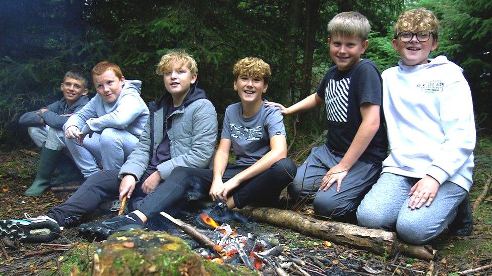 12 and 13-year-old boys sitting around campfire