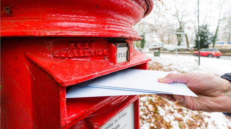 Someone posting cards into a post box