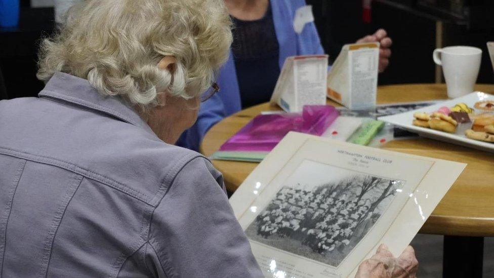 Elderly lady looking at an old Saints team photo