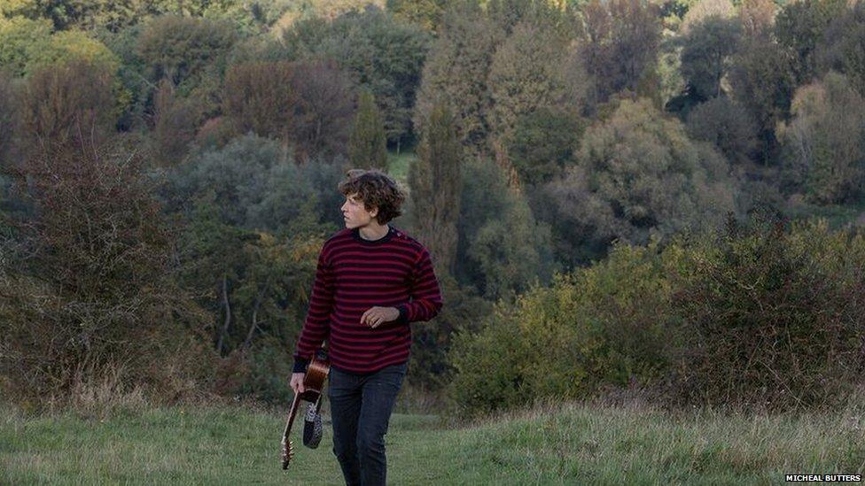 Josh carries his guitar up St Catherine's Hill