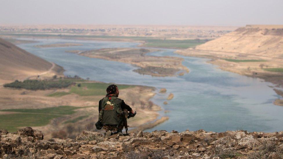 A Syrian Democratic Forces (SDF) fighter rests while looking over the River Euphrates north of Raqqa city, (8 March 2017)