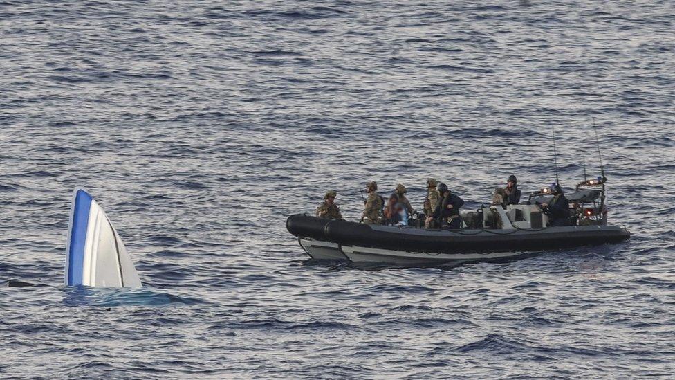 A submerged dinghy next to a Navy boat