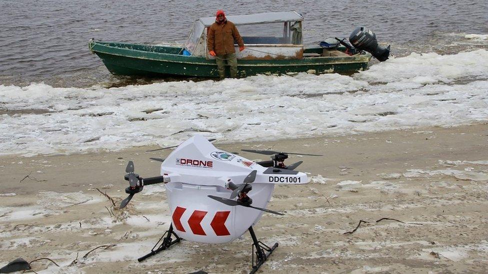 Drone sits on beach if front of a speed boat