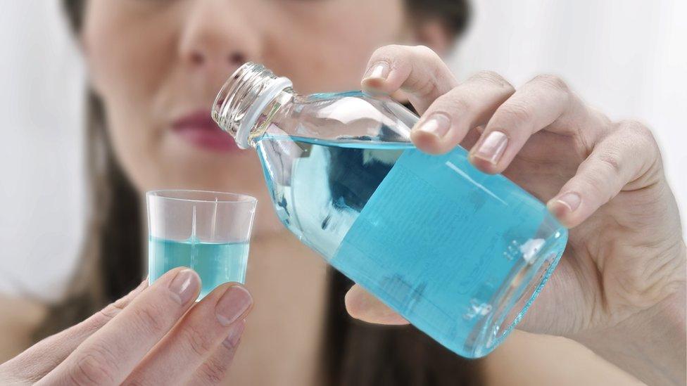 Woman using mouthwash