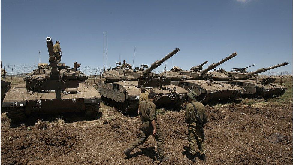 Israeli soldiers stand by Merkava tanks on the occupied Golan Heights