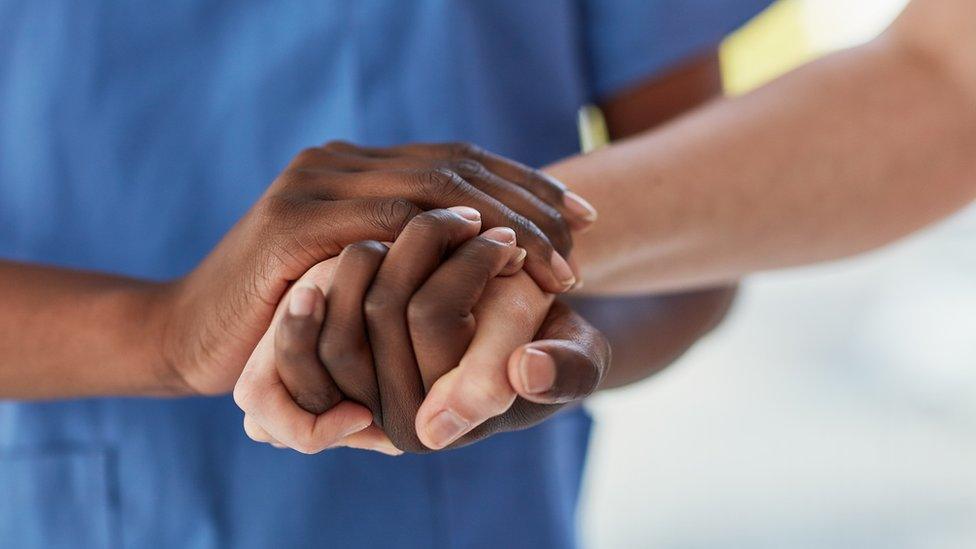 A nurse holds a woman's hand