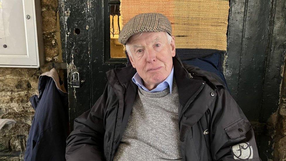 Michael Dolan sitting in a pub wearing a flat cap