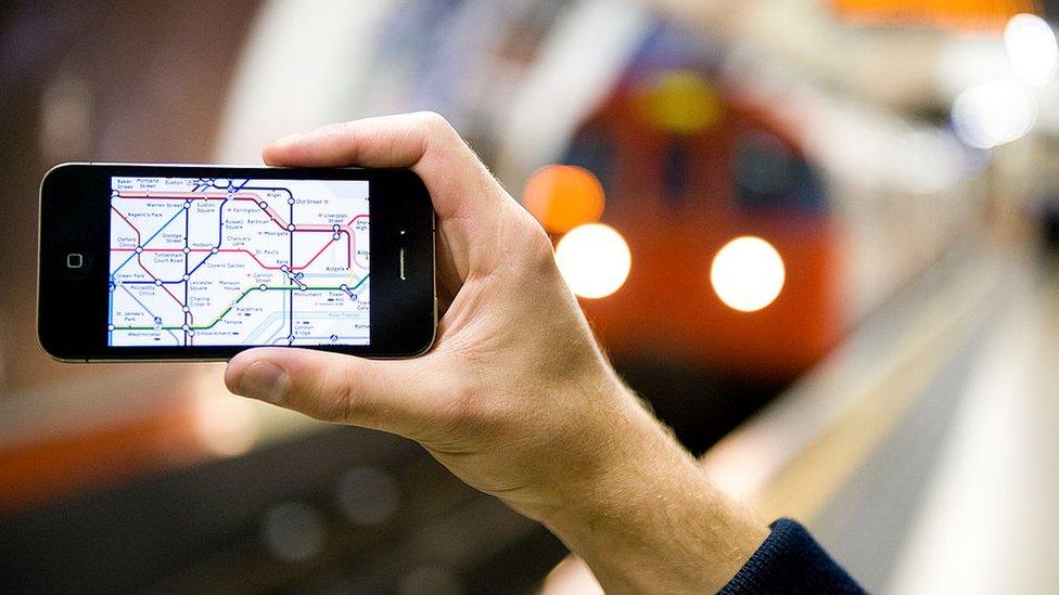 Man holds phone on London Underground