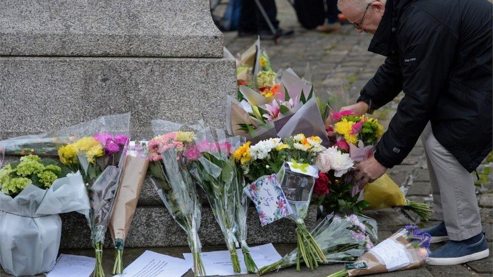 A man leaves flowers in Birstall