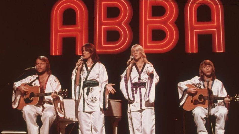 ABBA performing with large "ABBA" logo behind them