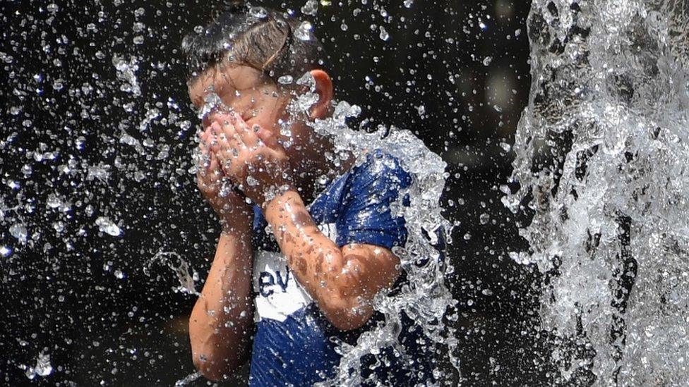 A child cools off under a fountain in Montpellier, southern France - 27 June