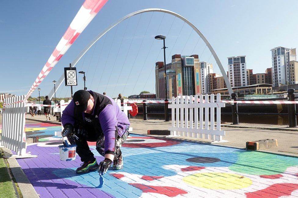 Alex Mulholland painting a mural on a disused bus lane on the Newcastle Quayside