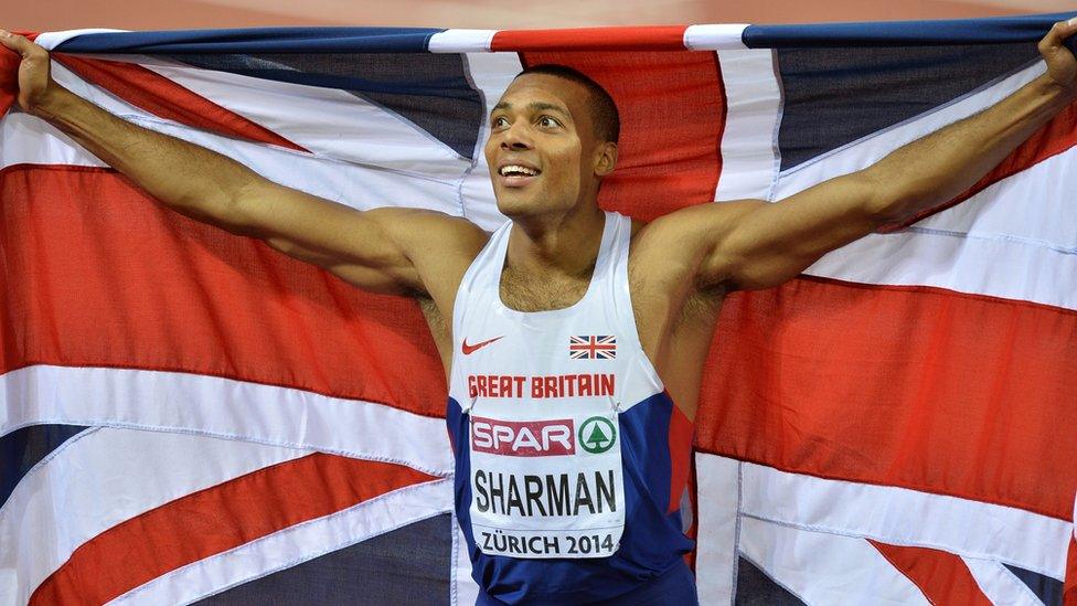 Athlete wearing competitor's bib and holding a large Union Flag