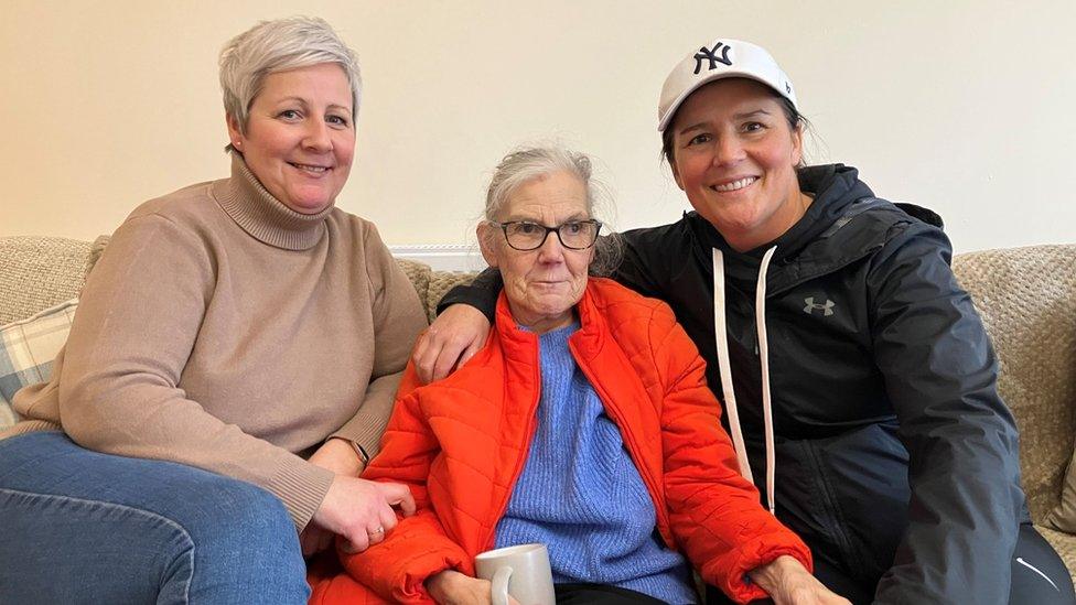 Pat sitting with two friends on her sofa