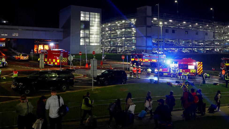 People leave the London Luton airport as emergency services respond to a fire