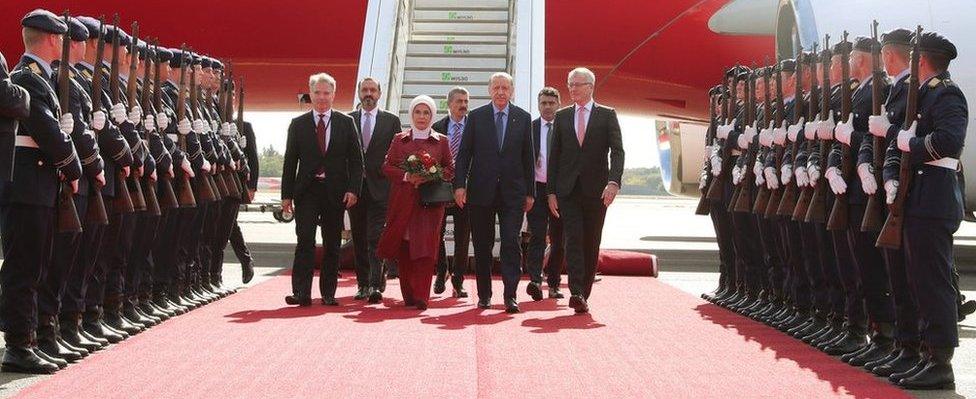 Mr Erdogan and his wife, along with senior officials, are accompanied down a red carpet flanked by a military honour guard.