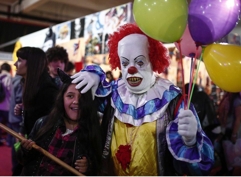 A man dressed as the clown from Stephen King's novel 'It' plays with a girl at the Anime Friends, a gaming and comic event in Buenos Aires, Argentina, on 24 July, 2016.