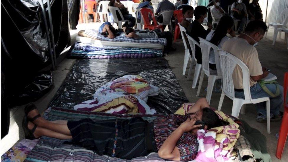 People rest as they wait for the remains of their relatives outside a morgue in Santa Catarina Pinula on 5 October, 2015.