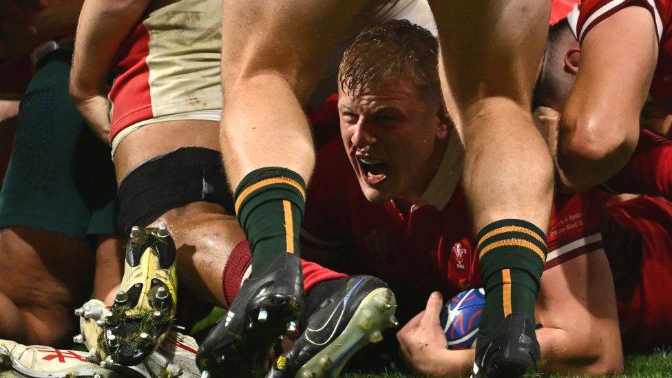 Jac with the ball in his hand on the ground beneath a pile of players shouting