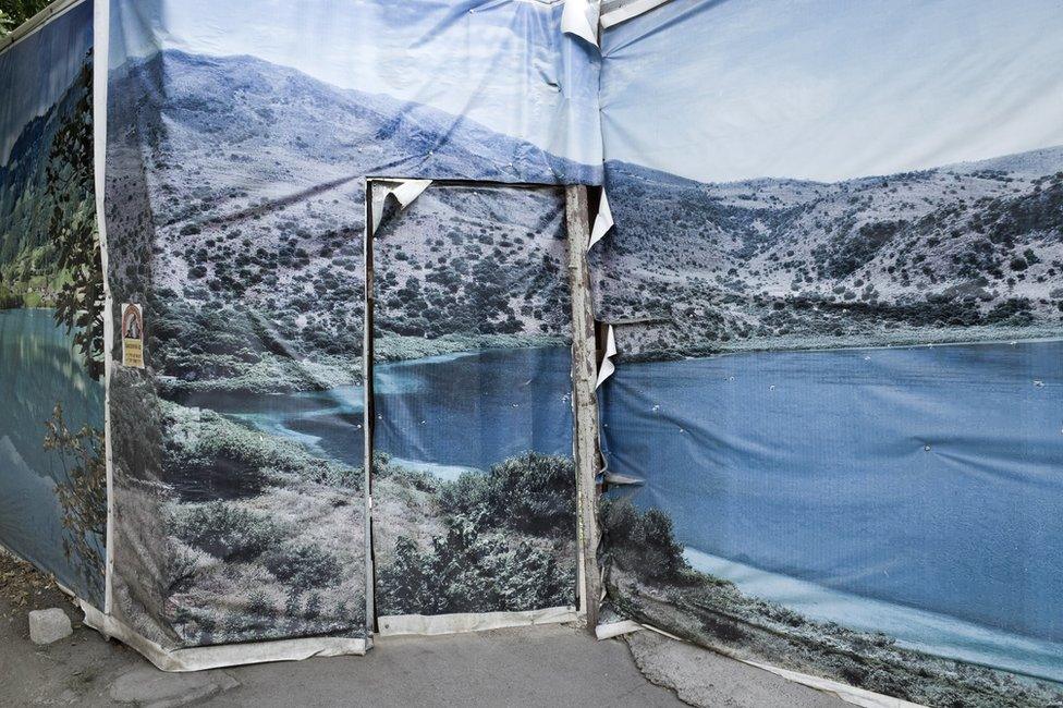 A photo of a poster of a scene of a lake in Kazakhstan plastered over a door