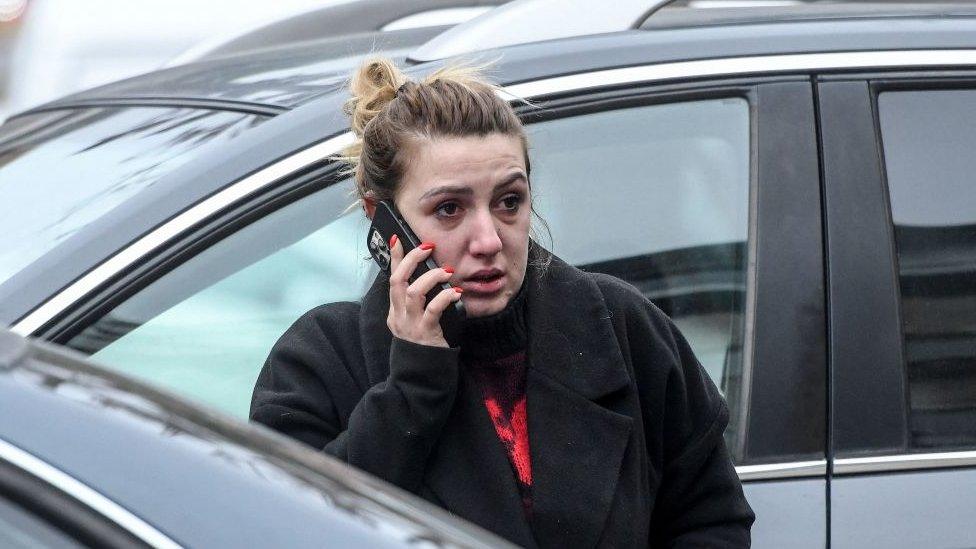 A relative of victims of the bus crash reacts as she speaks on the phone in front of the offices of Besa Trans travel agency