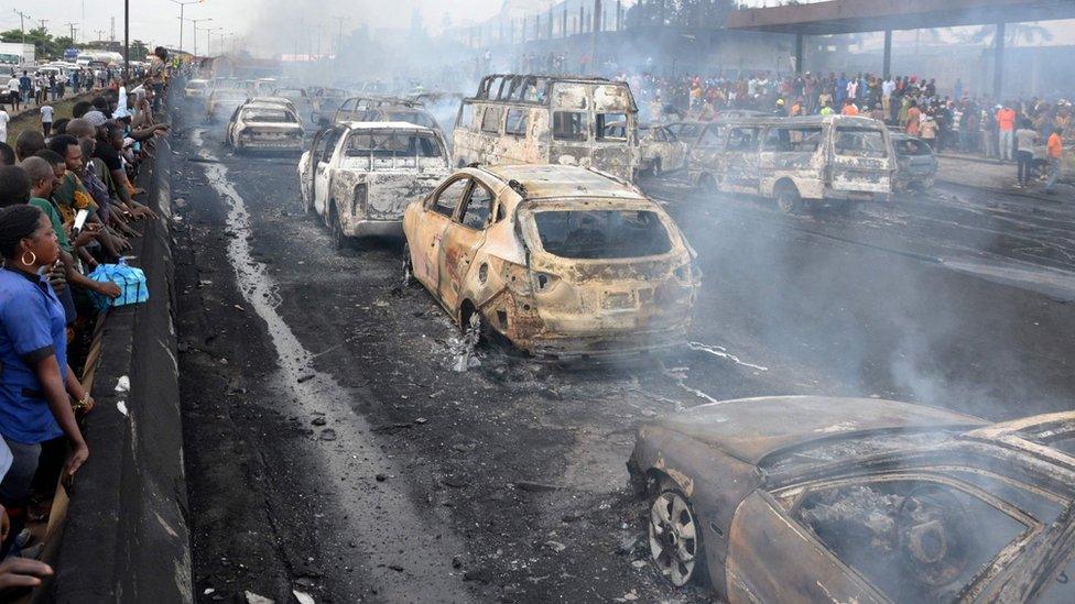 Bystanders and emergency service rescuers observe at the scene of an oil tanker explosion on a highway in Lagos, 28 June 2018