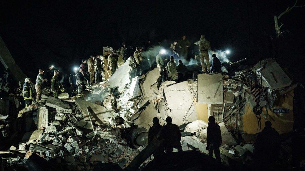 Rescuers remove debris to search for survivors at a destroyed apartment building hit by a rocket during the night in downtown Kramatorsk