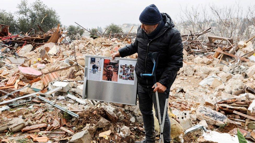 A Palestinian man holds up the remains of a refrigerator destroyed when Israeli authorities demolished a home in the Sheikh Jarrah neighbourhood of East Jerusalem on 19 January 2022