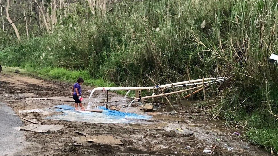 A child gathers water from a pipe in rural Puerto Rico