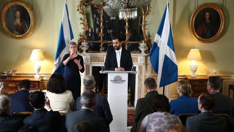 Humza Yousaf on press conference stand with scottish flag