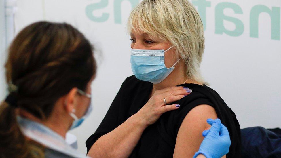 A woman receives a dose of Covid-19 vaccine in a vaccination centre at Newmarket Racecourse