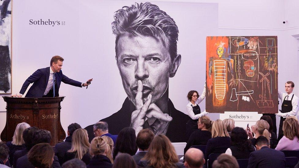 Sotheby’s auction featuring David Bowie’s art collection, with Jean-Michel Basquiat’s Air Power painting displayed beside a large portrait of Bowie.