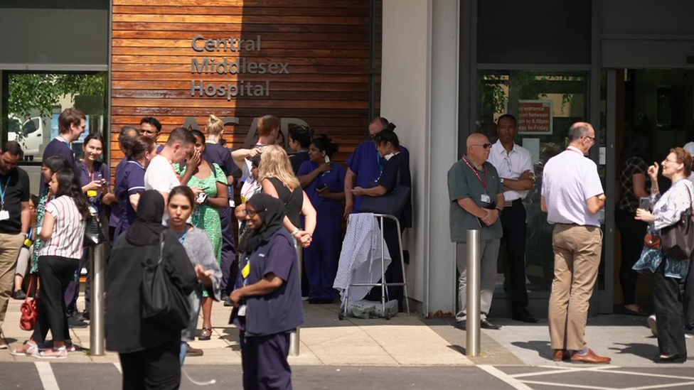 Staff wait outside the hospital