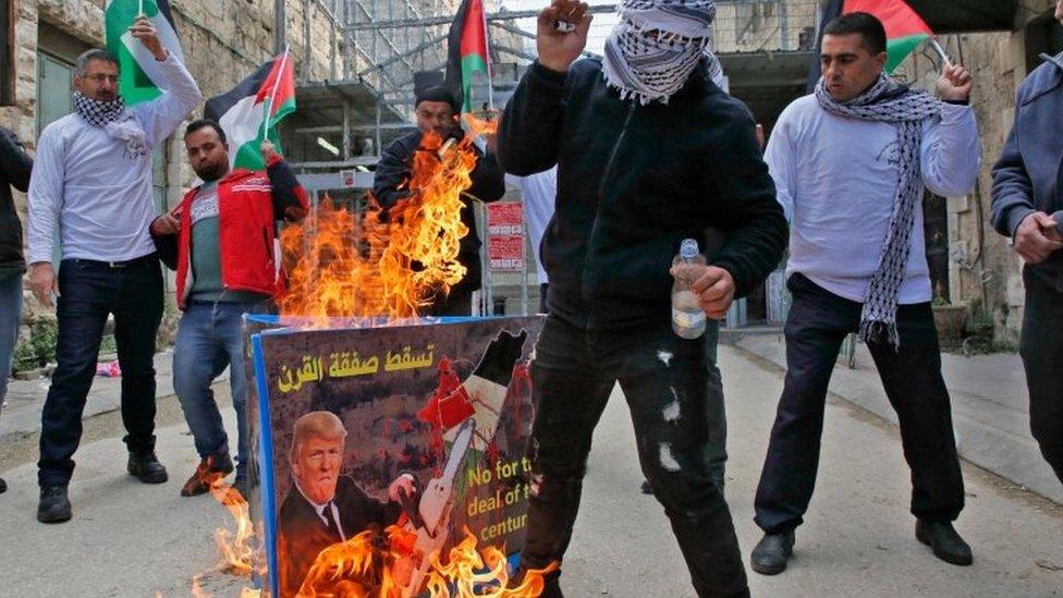 Palestinian protestors set ablaze a poster with a picture of US President Donald Trump during a demonstration in Hebron in the Israeli occupied West Bank on 22 February 2019