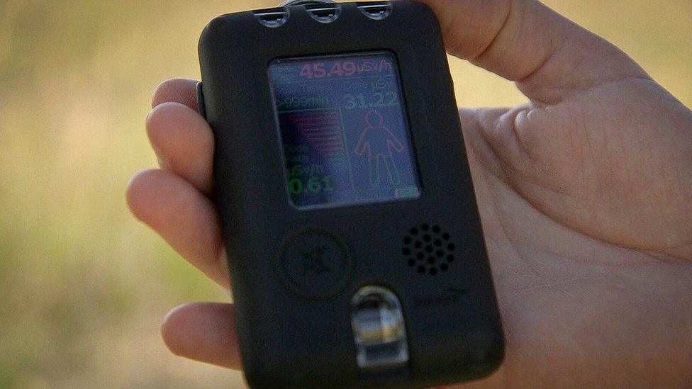 A researcher holds a radiation dosimeter